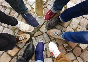 Circle of sneakers on cobblestone pavement representing diversity and urban fashion.